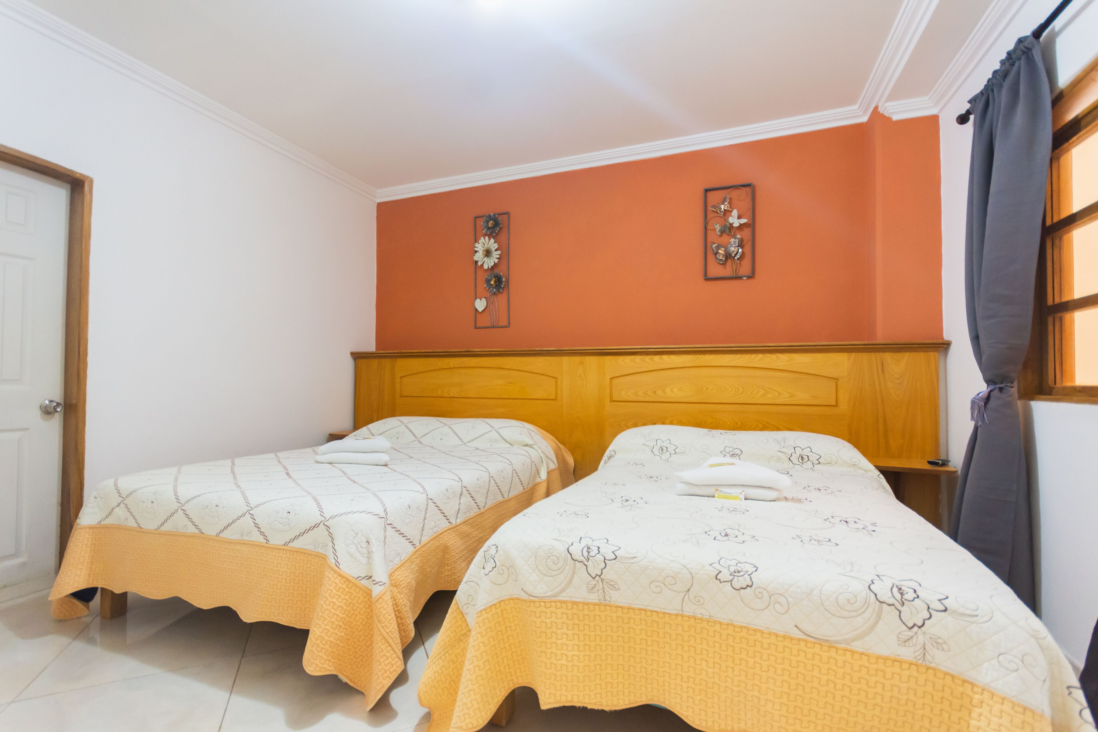 A bedroom with two beds, a wooden headboard, and a door.