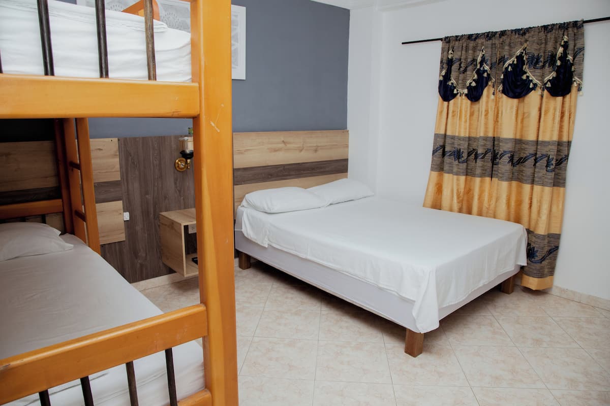 Um quarto com uma cama de solteiro, uma cama individual, uma mesa de cabeceira de madeira e uma cortina.