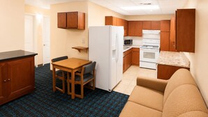 A compact kitchenette with a refrigerator, microwave, stove, and wooden cabinets. - Extended Stay Snyder (Snyder)