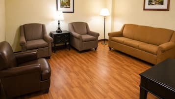 A living room with a brown leather sofa, two armchairs, a small table, and two floor lamps.