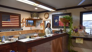 A reception desk with a clock, American flags, and a sign for breakfast buffet. - Extended Stay Snyder (Snyder)