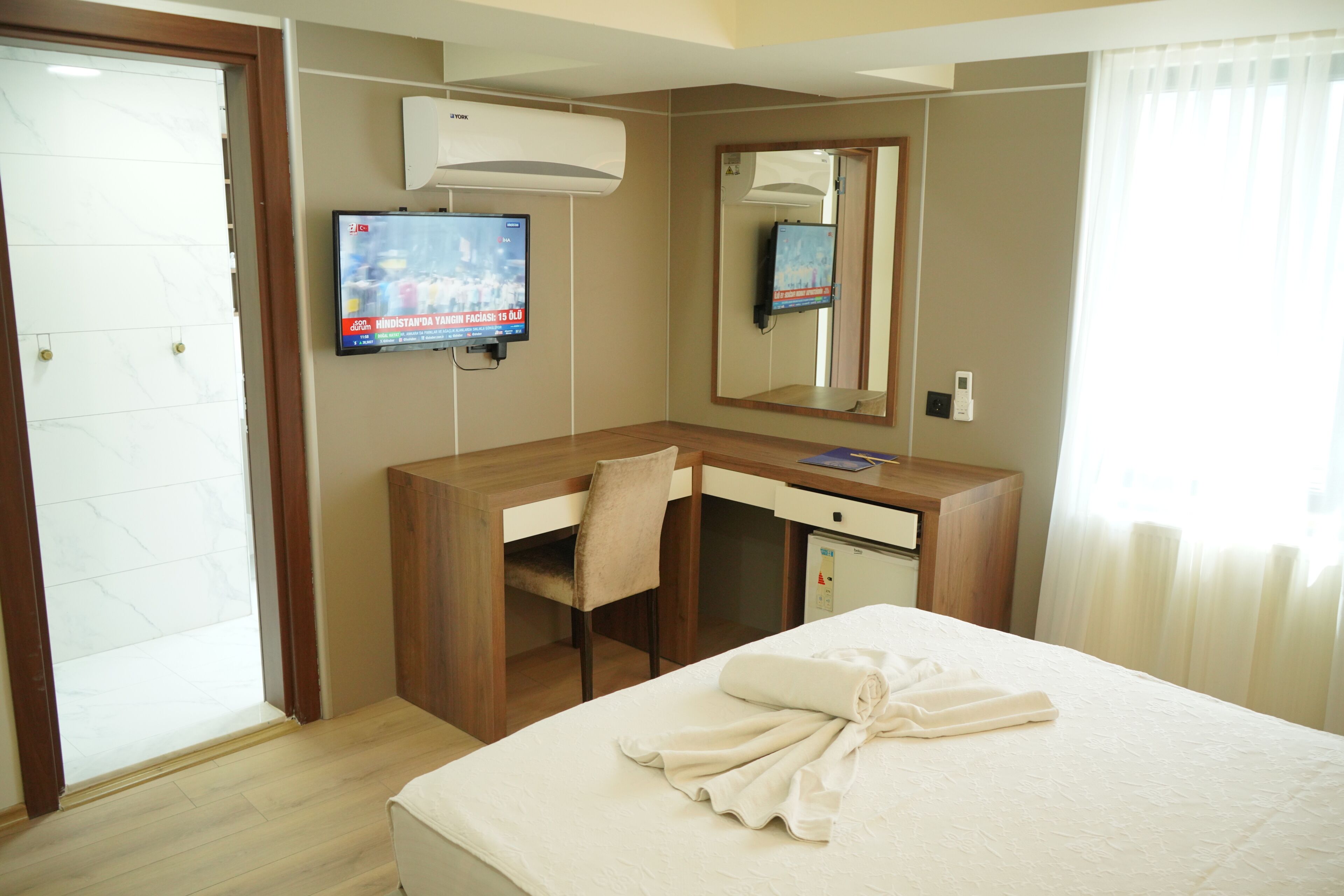 Une chambre d’hôtel comprenant un lit, un bureau, une chaise, une télévision et un miroir.