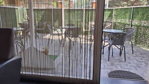 Et værelse med en skydedør, der fører ud til en terrasse med et bord og stole.