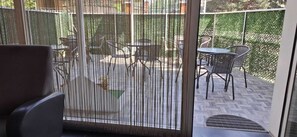 Une pièce dotée d’une porte-fenêtre coulissante donnant sur un patio extérieur aménagé avec une table et des chaises.