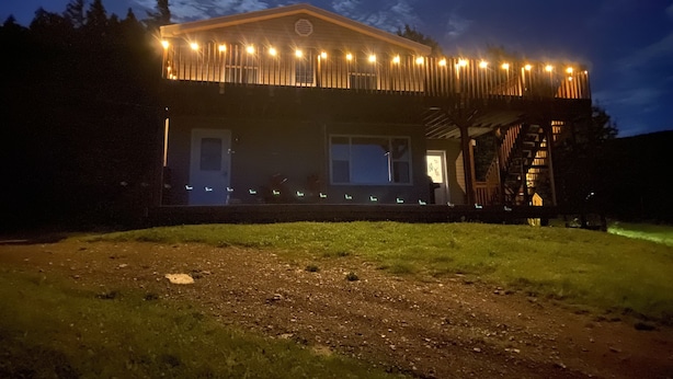 Ein zweistöckiges Gebäude mit Balkon und überdachtem Bereich, beleuchtet mit Lichterketten.