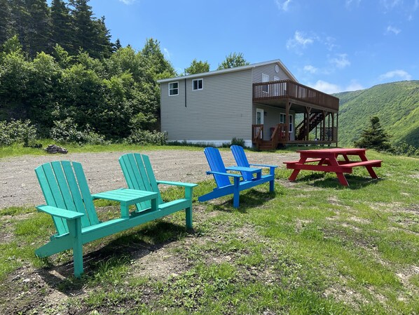 A cabin with a porch, two Adirondack chairs, and a picnic table. - (Meat Cove)Hines Ocean View Lodge (Capstick)