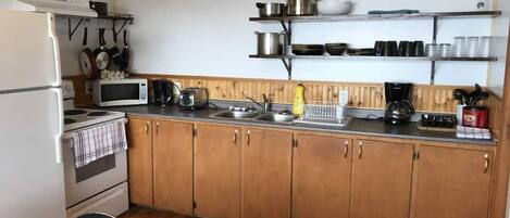 A compact kitchen with wooden cabinets, a microwave, a stove, and a sink.