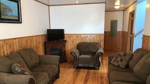 Ein Wohnzimmer mit zwei Sofas, einem Kamin und einem Fernseher.