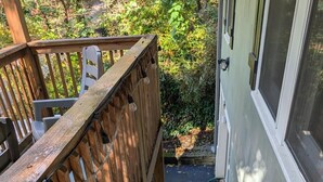 Un escalier en bois menant à un porche doté d’une balustrade et d’une porte avec un moustiquaire.