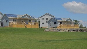 A row of houses with solar panels on the roofs, wooden decks, and a stone wall in the foreground.