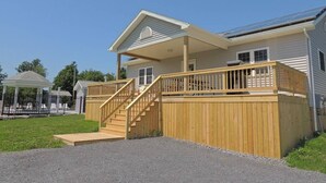 A two-story house with a covered porch, a wooden deck, and a staircase leading to the upper level.