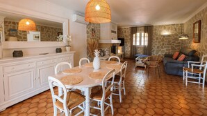 A spacious living area with a stone wall, a dining table with white chairs, and a cozy seating area with a sofa and chairs.