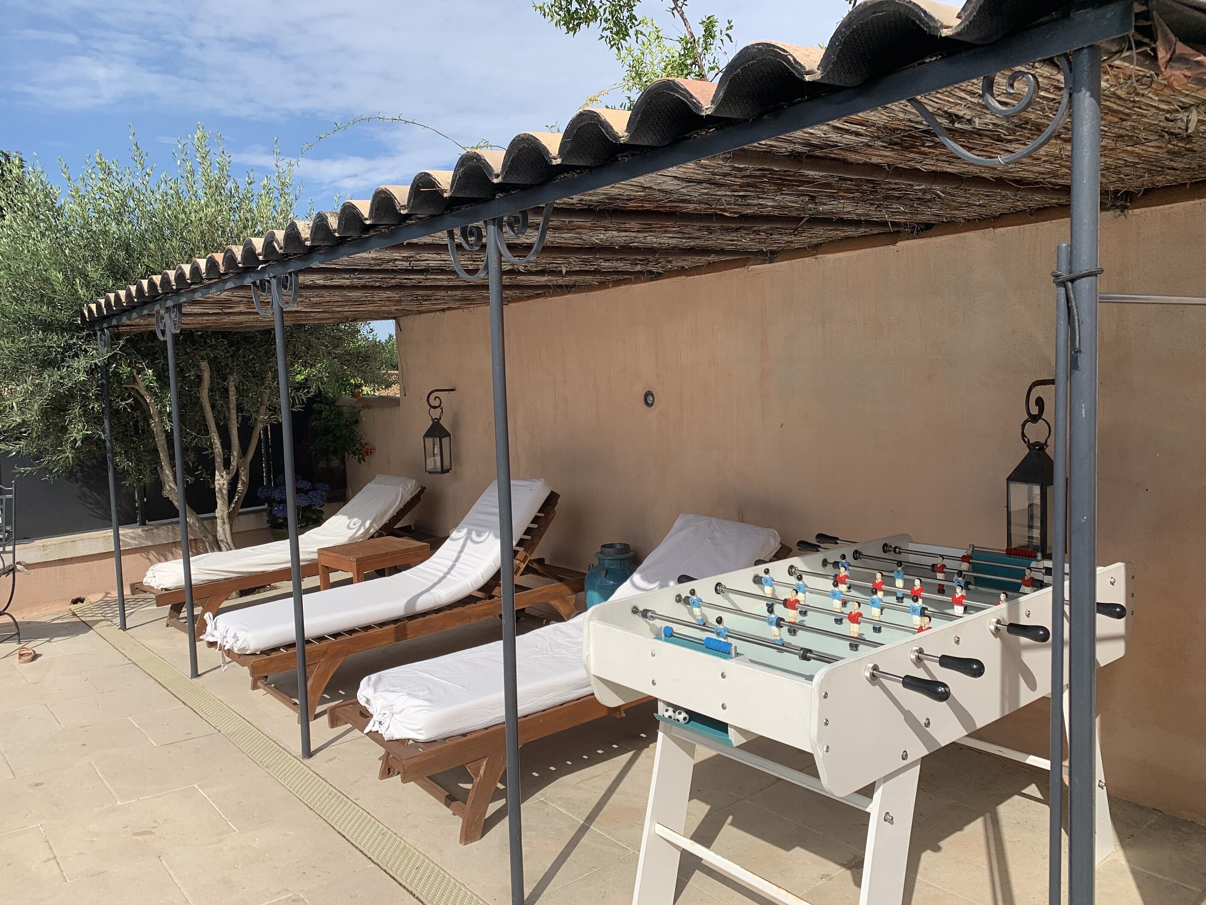 A covered outdoor area with lounge chairs and a foosball table.
