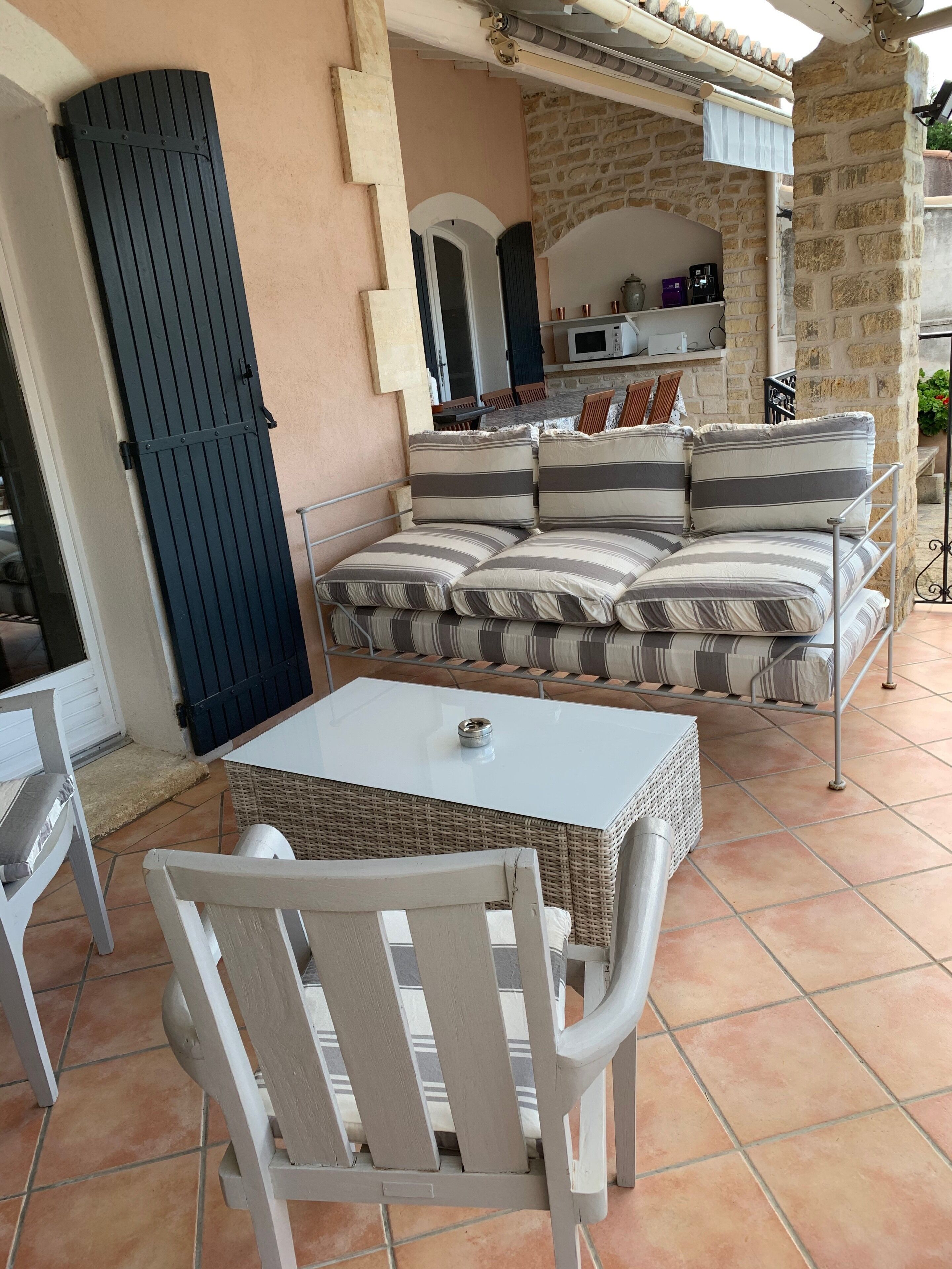 Un espacio exterior acogedor con sofá y sillones, un patio empedrado y una pared de piedra.