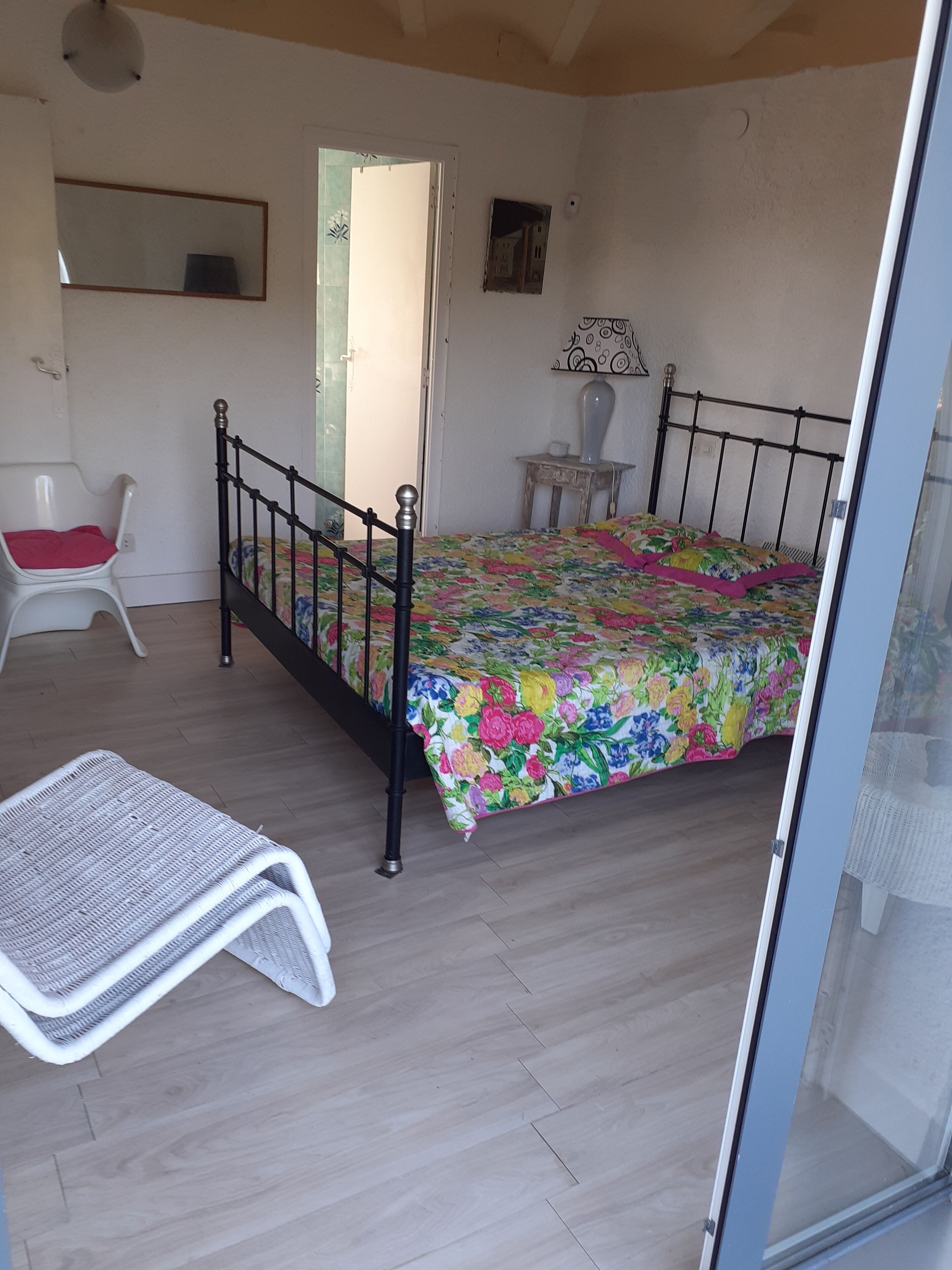 A bedroom with a bed, a chair, a small table, and a mirror.