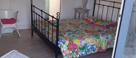 A bedroom with a bed, a chair, a small table, and a mirror.
