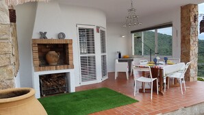 Eine Terrasse mit Kamin aus Backstein, einem Esstisch und Stühlen.