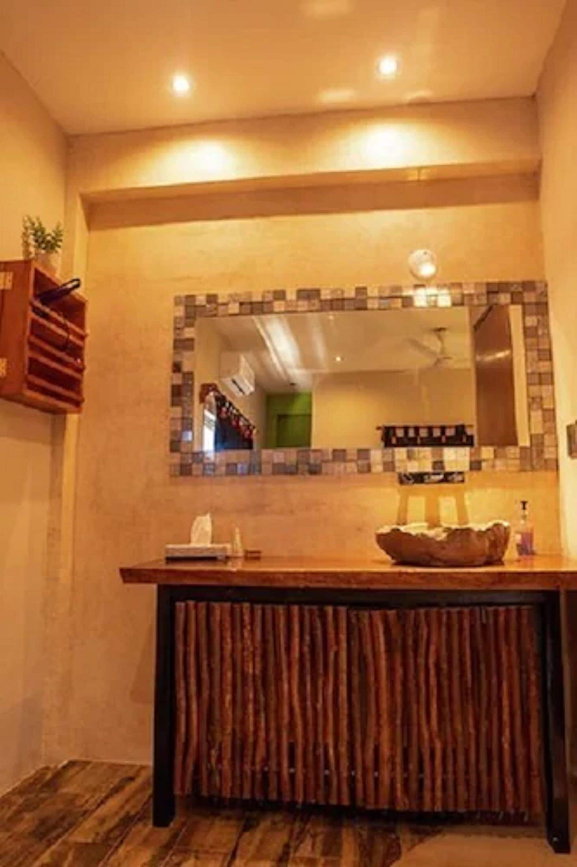 A bathroom with a wooden vanity, a mirror with a mosaic border, and a towel rack.