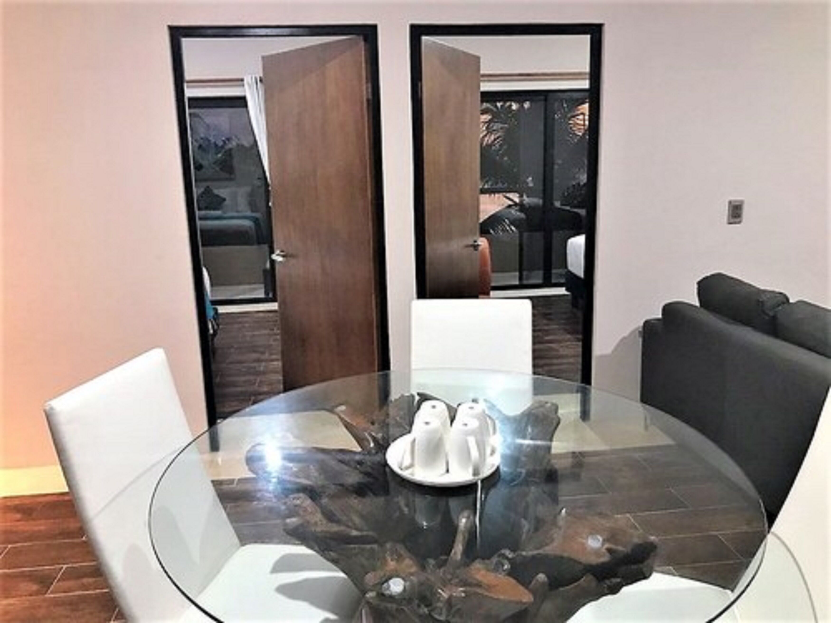 A modern dining area with a glass table, white chairs, and a central coffee pot.