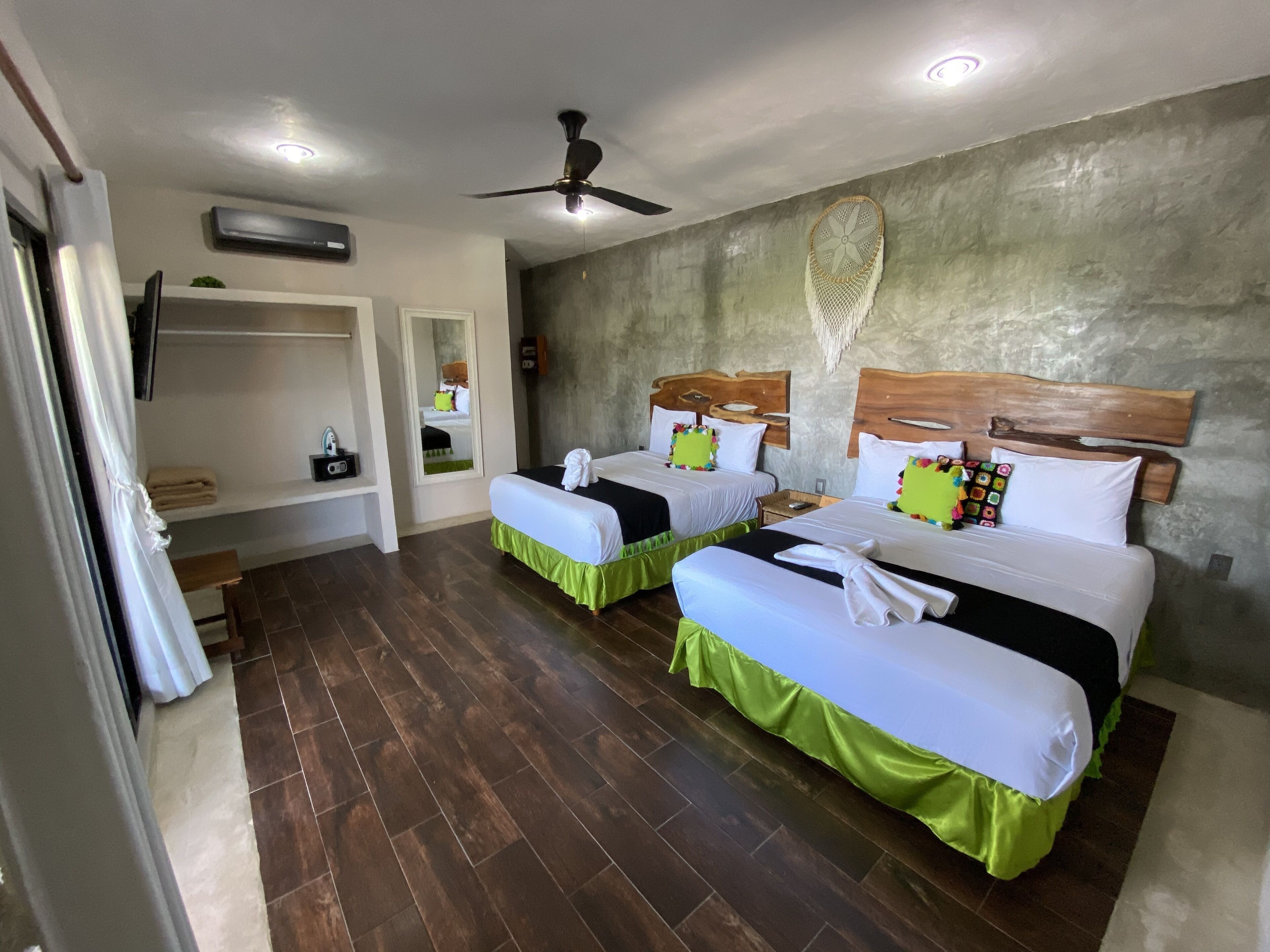Quarto de hotel com duas camas, um ventilador de teto e um espelho grande.