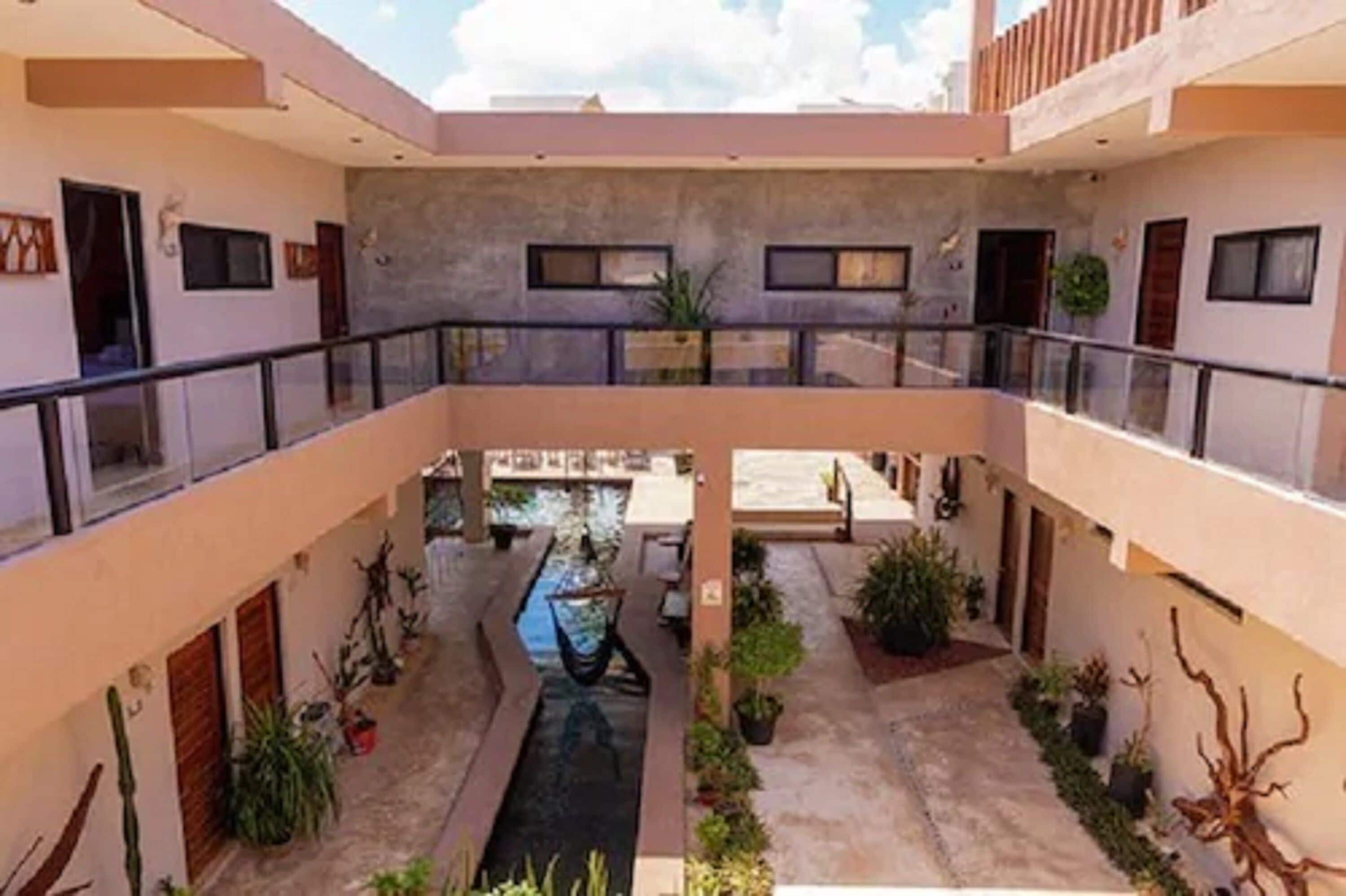 A modern building with a central courtyard, balconies, and potted plants.