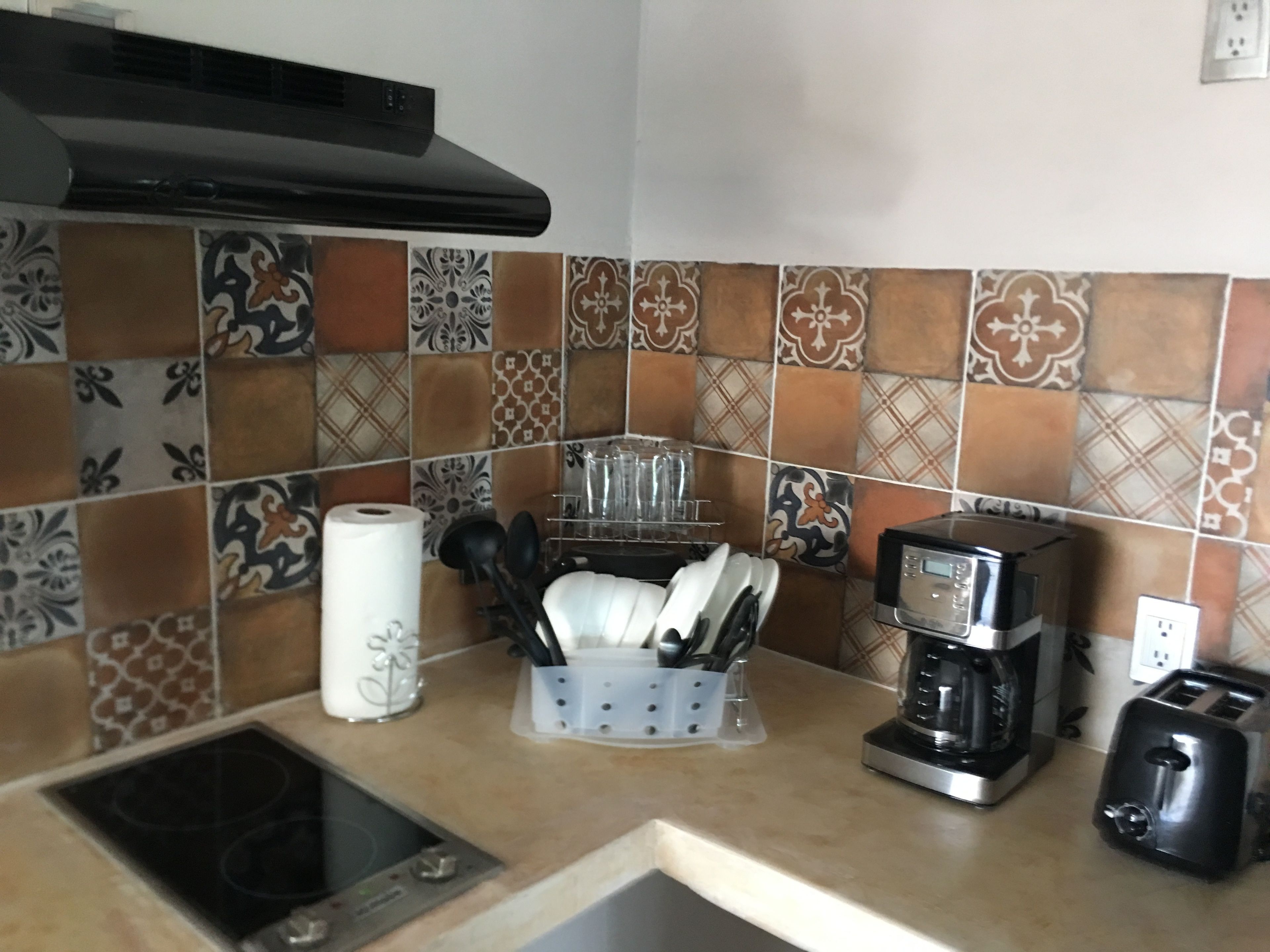 A kitchen with a gas stove, coffee maker, toaster, and a dish rack with utensils.