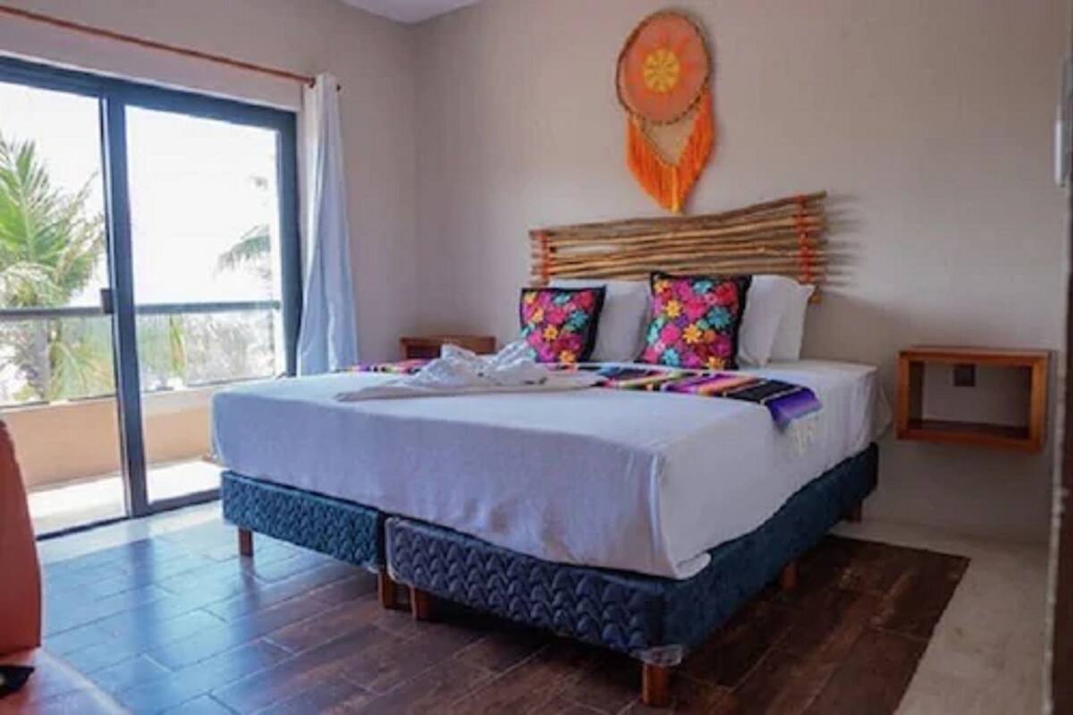 A bedroom with a large bed, a dreamcatcher decoration, and a view of the outdoors.