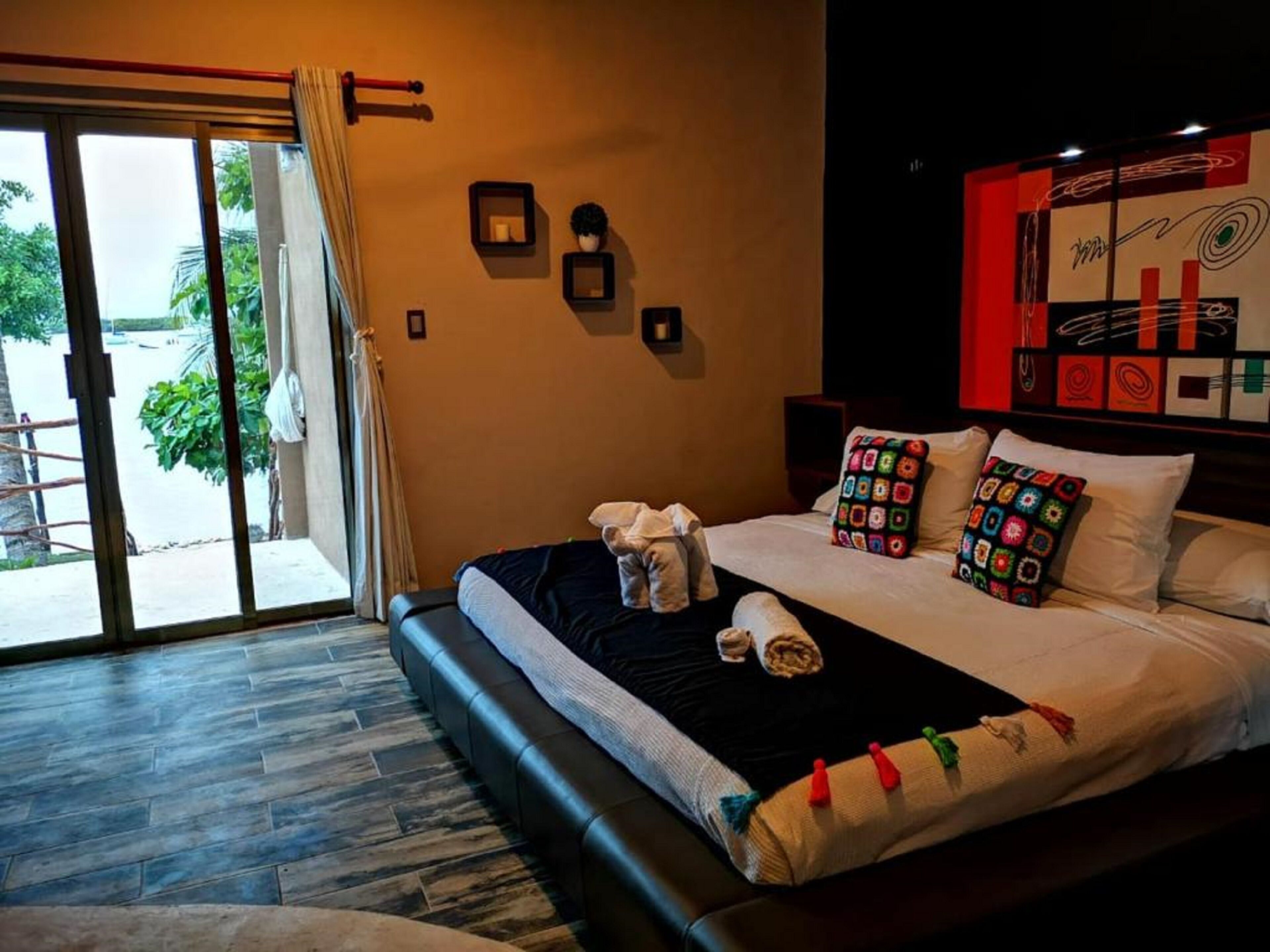 A hotel room with a large bed, a sliding glass door to the outside, and a wall with framed pictures.