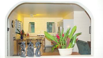 A kitchen with a central island, a sink, and a stove. There is a potted plant on the counter.