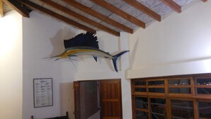 A room with a wooden ceiling, a large fish mounted on the wall, a wooden bench, and a window with multiple panes. - SECHIN HOUSE ,  ubicada en el Balneario de Tortugas Caleta Norte (Tortuga Casma)
