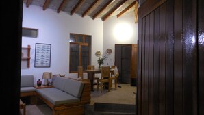 A cozy living room with a sofa, wooden dining table, and chairs. There is a staircase leading to another level. - SECHIN HOUSE ,  ubicada en el Balneario de Tortugas Caleta Norte (Tortuga Casma)