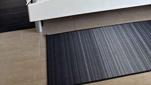 A double bed with white linens, two bedside tables, a lamp, and a dark rug. - Holiday apartment with balcony (Šilo)