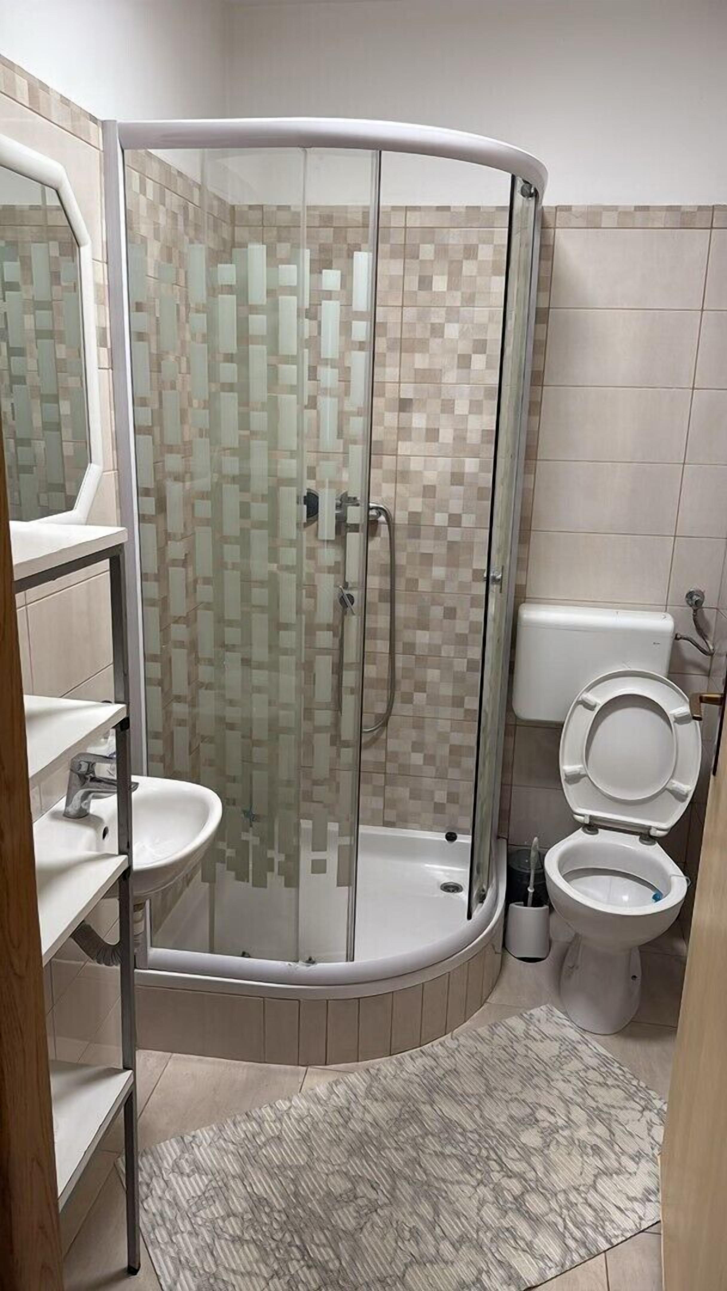A modern bathroom with a glass-enclosed shower, a toilet, and a sink.
