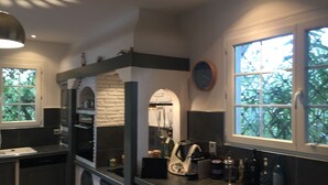 A modern kitchen with a stone backsplash, stainless steel appliances, and a large window with a view of trees.