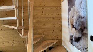 A spiral staircase with wooden steps and metal railings, leading to a room with a large framed picture of a polar bear.