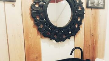 Un bagno con un mobile vanitario in legno, un lavandino nero e uno specchio decorativo con una cornice elaborata.
