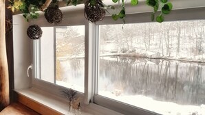 Une fenêtre dotée d’un rebord en bois et offrant une vue sur un paysage enneigé.