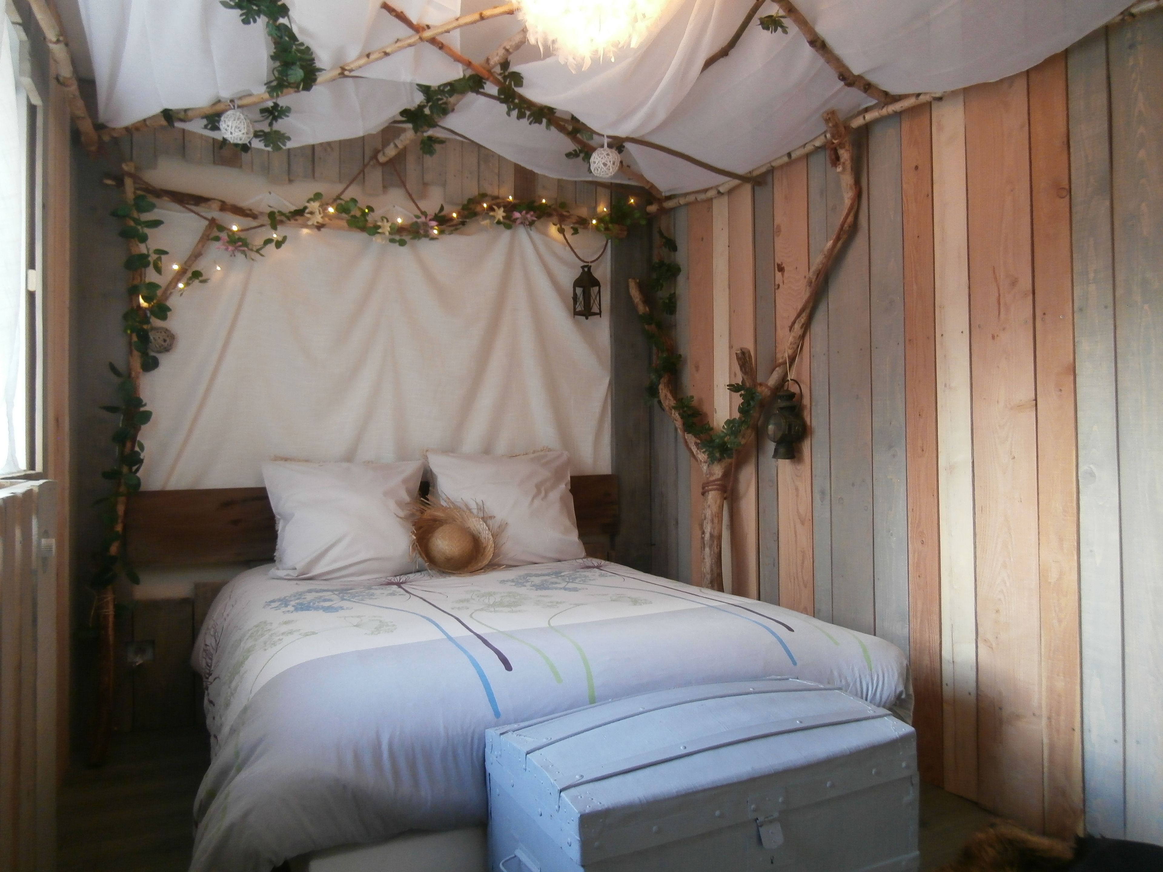 Una camera da letto rustica con un letto di legno, una tenda a baldacchino e una piccola panca.
