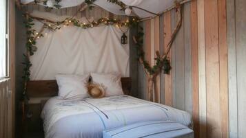 Un dormitorio rústico con una cama de madera, dosel y un pequeño banco.