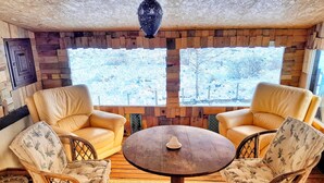 Une pièce chaleureuse avec deux canapés en cuir, une table ronde en bois et des chaises en osier.
