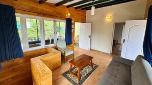 Een gezellige kamer met houten wanden en plafond, een bank, een houten tafel en een stoel.