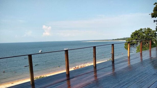 Eine Holterrasse mit Blick auf einen Strand, der einen klaren Meerblick und eine entfernte Küstenlinie bietet.