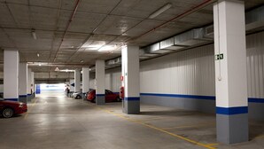 Een parkeergarage met meerdere verdiepingen, betonnen vloeren en witte pilaren.