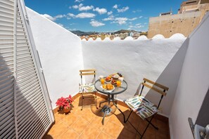 A small outdoor patio with a table, chairs, and a potted plant.