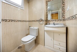 A bathroom with a toilet, sink, and mirror.