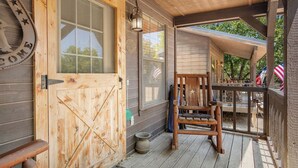 Eine Holzveranda mit einer Holztür, einem Stuhl und einem Tisch.