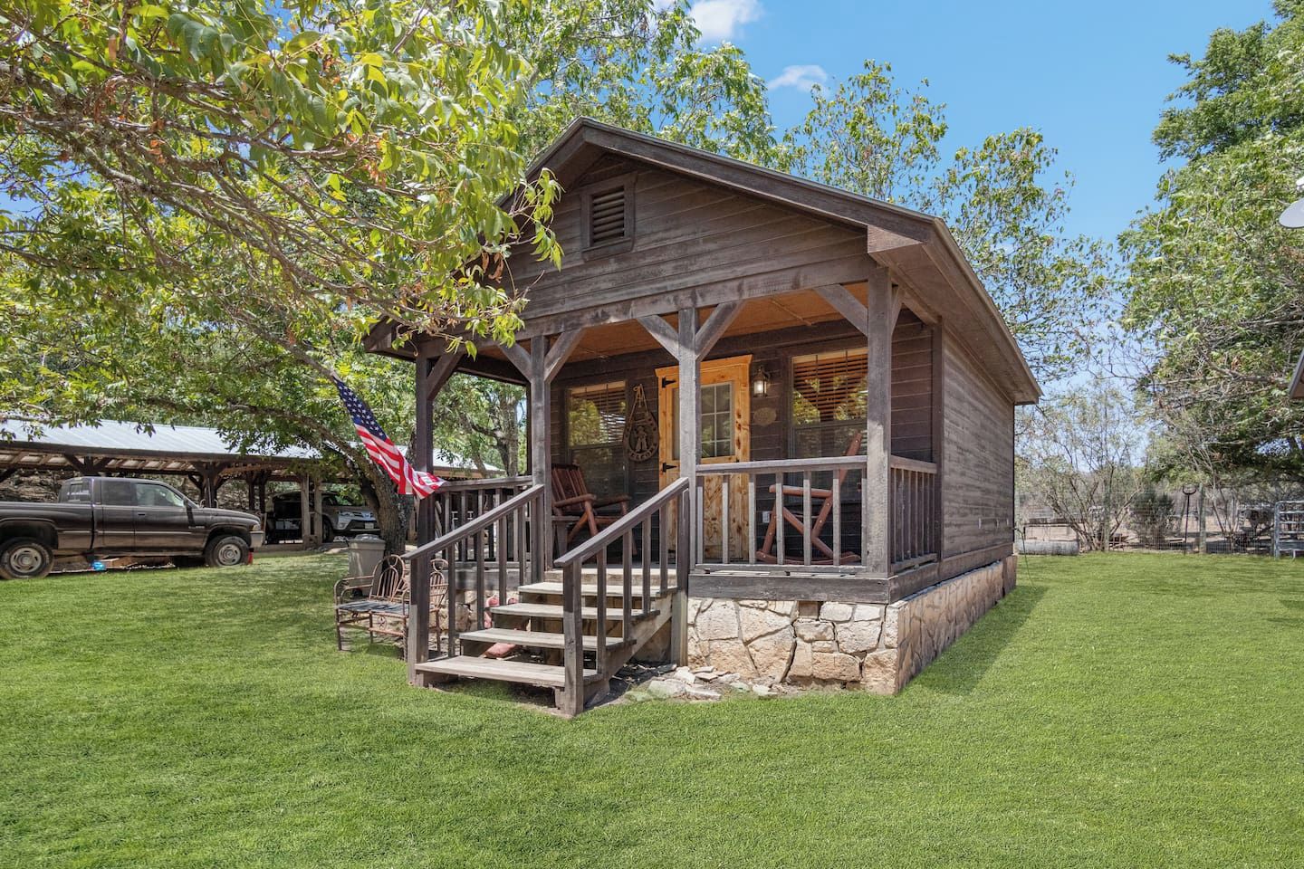 A rustic cabin with a porch, steps, and a flag.