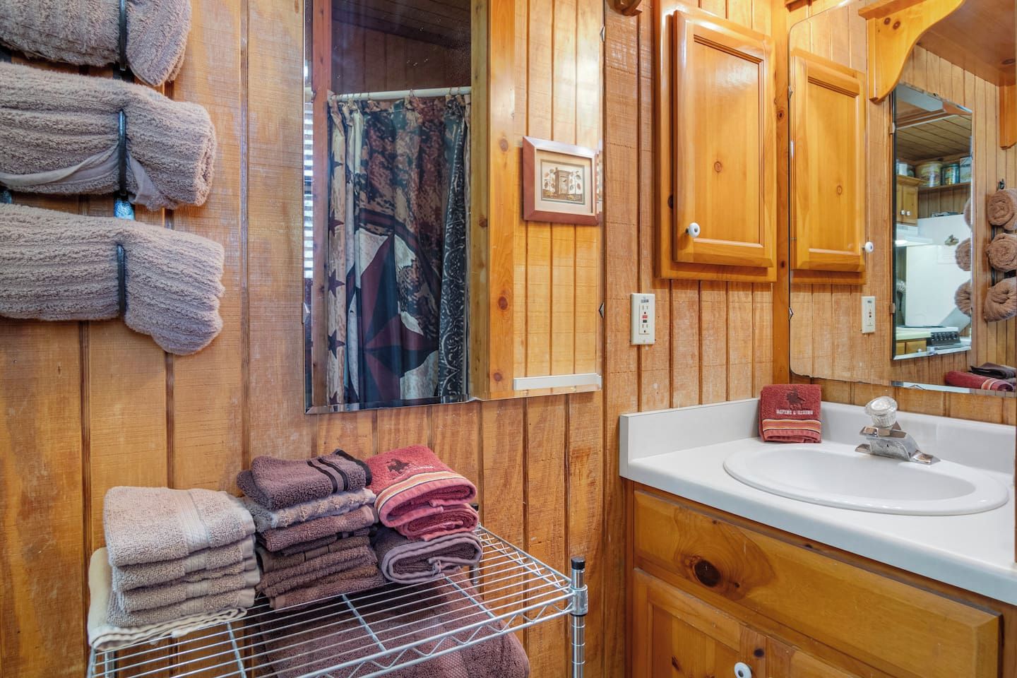 A wooden bathroom with a sink, mirror, and towels.