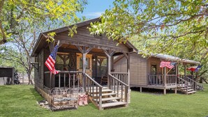 Eine Holzhütte mit Veranda und überdachter Terrasse, sowie zwei amerikanischen Flaggen.