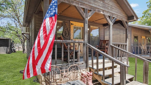 Ein Holzhaus mit Veranda, einer Flagge und einem Willkommensschild.